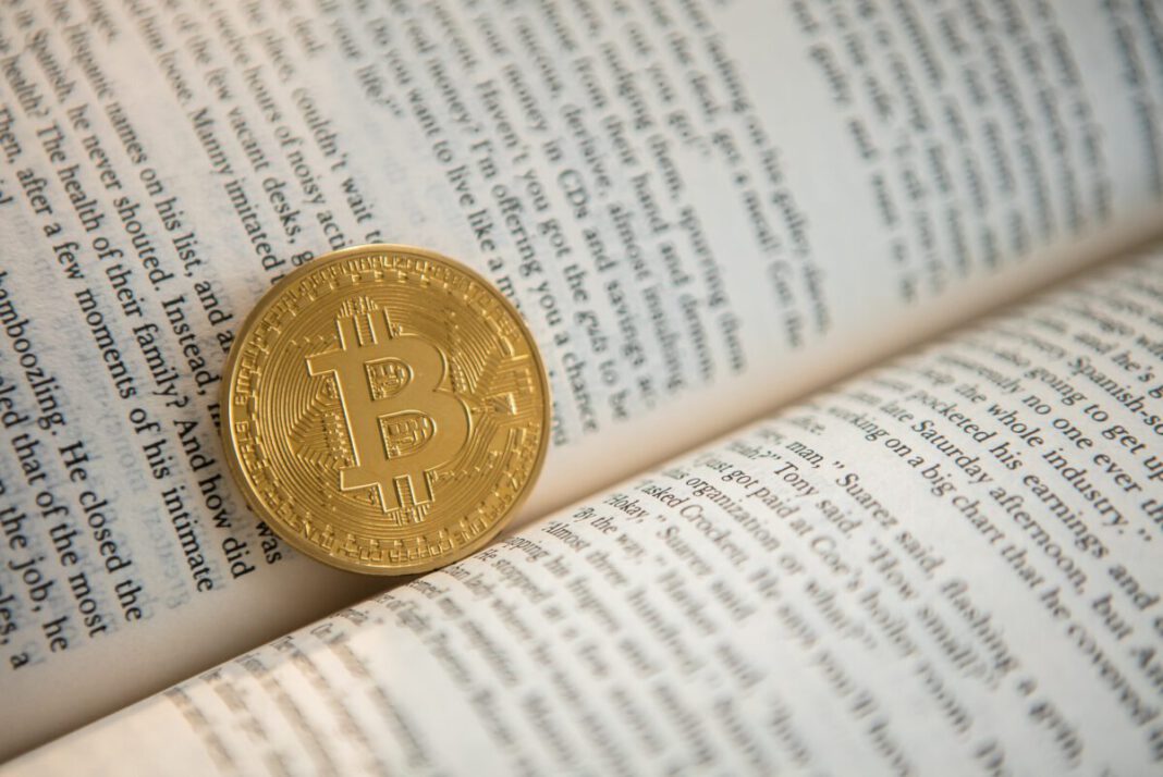 Bitcoin-Begriffe: Eine Bitcoin-Münze liegt in einem Buch