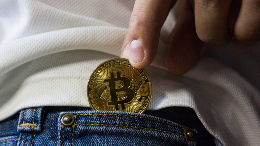 Bitcoins aufbewahren: Jemand steckt einen Bitcoin in die Tasche